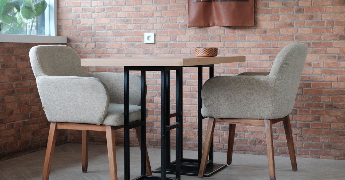 Furniture leg protection: wooden legs on two fabric chairs and a black steel table base by a brick wall